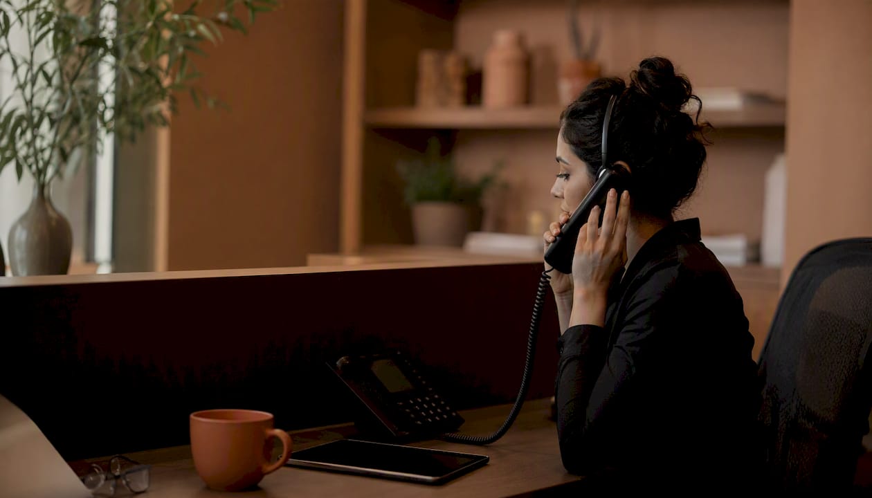 Hands managing bilingual front desk phone
