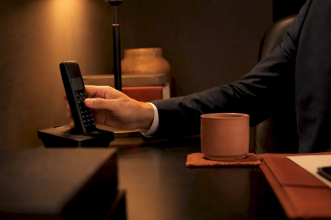 Hand pressing mute on phone at receptionist desk