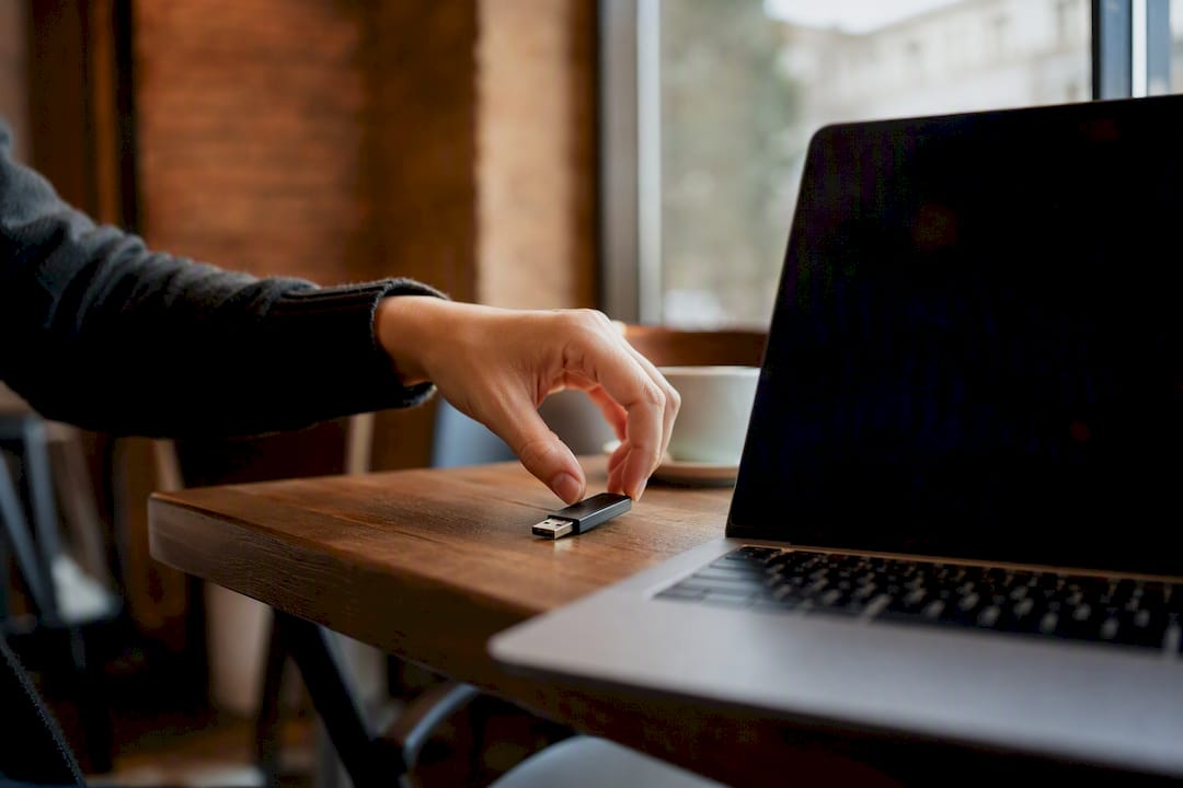 Mano colocando una memoria USB junto a una laptop